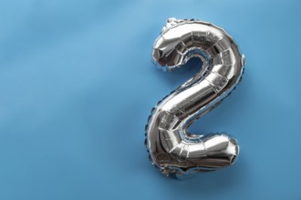 2 two metallic balloon isolated on blue background. Greeting card silver foil balloon number Happy