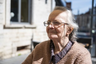 Portrait of an 84 yo white woman with glasses looking concentrated, Tienen, Belgium, Europe