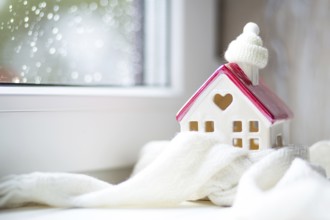 Cozy house is wrapped in a hat and scarf in a snowstorm -window sill decor. Winter, snow, home