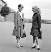 Girls in the 1950s. Two teenage girls dressed in outfits typical of the decade. Typical schoolgirls