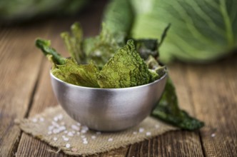 Healthy Savoy Chips on a wooden table as detailed close-up shot (selective focus)
