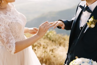 Bride in a beautiful dress puts a ring on the groom's finger.