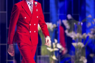 Male model walks the runway in red suit during a Fashion Show. Fashion catwalk event showing new