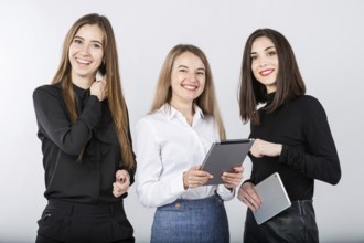 Three smiling business women standing in a row isolated on white background. Business Group people.