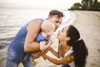 A young, beautiful family of three. Mum, Dad and daughter in the arms of my father play, rejoice,
