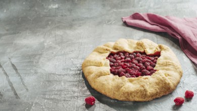 Perfect raspberry galette. Delicious rustic homemade tart with frozen or fresh raspberries on gray