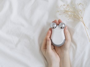 Microcurrent concept. Face massager with micro currents for home use and skincare on white bed.