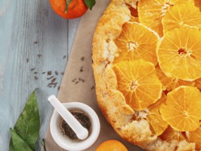 Top view of caraway and orange tart on baking paper over gray wooden table with copy space.Winter