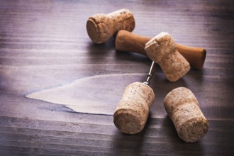 Four corks and corkscrew on vintage wooden board alcohol concept