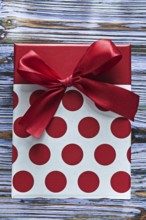 Red present box with ribbon on vintage wooden board