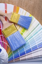 Two paintbrushes on color palette and wooden board