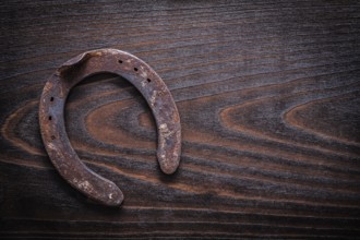 Rusted obsolete horsehoe on vintage dark wood board copy space image construction concept