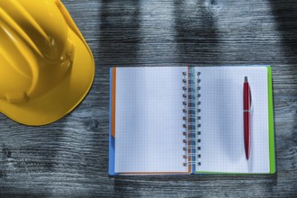 Notepad pen building helmet on wooden board