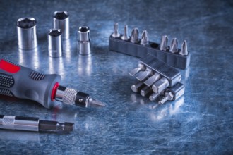 Toolset of screwdriver with stainless replaceable bits and torx on scratched metallic background