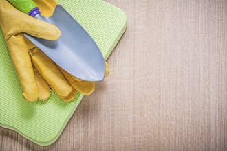 Protective gloves metal hand spade foam gardening kneeling pad on wooden board agriculture concept