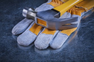 Safety gloves with claw hammer on scratched metallic background construction concept