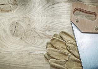 Safety gloves hacksaw on wooden board construction concept
