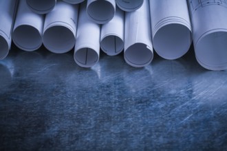 Rolls of white blueprints on scratched metallic background building and architecture concept