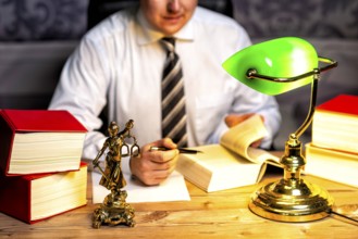 Office of a lawyer with books and a statue of Lady Justice, goddess Justitia, on the desk
