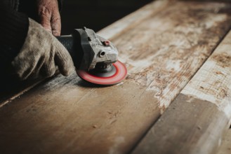 Gloved hands using a sanding tool on wood, focusing on surface texture and craftsmanship