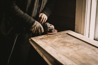 A person using a power tool to sand wood at a workbench