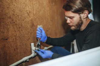 Person using a wrench on a pipe connection while wearing gloves