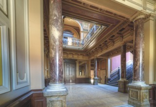 An opulent entrance hall with wood panelling, columns and a colourful ceiling painting, Villa