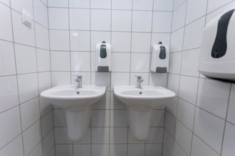 A clean and contemporary public restroom that features two modern washbasins along with convenient