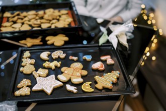 Gingerbread cookies with colorful ornaments lie on a baking sheet on the table.