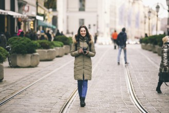 Beautiful young woman tourist with long hair stands on the background of the central street in the