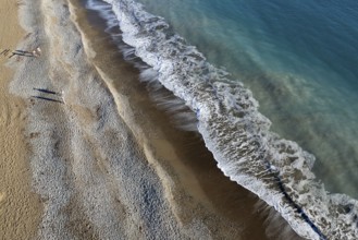 Aerial drone point of view of person walking on sand in a beach. Stormy waves idyllic beach in