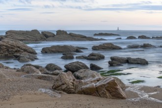 Rocks on the beach in the evening with moving water which brings an effect to the surface of the