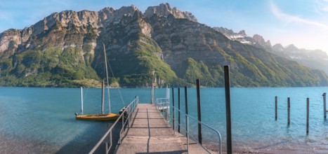 Spring landscape with a pier on the Walensee lake leading toward the Alps mountains, in