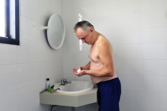 Man 60 plus shaves wet in the bathroom