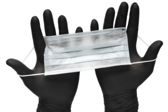Medical man holds antivirus face mask in hands in black medical gloves. Isolated on white