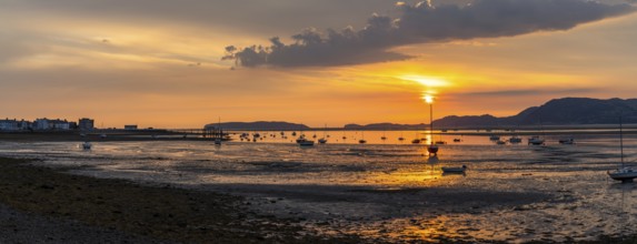 Colorful sunrise on the Menai Strait and mountains of Snowdonia at low tide with Beaumaris village