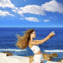 Blond kid teen girl photo selfie on smartphone in a beach at Mediterranean