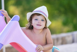 Baby kid girl with hat in summer on green field background