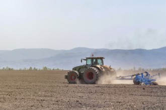 Farmer in tractor preparing land seedbed cultivator. Agriculture tractor landscape