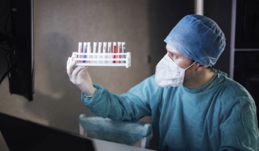 Medical professional holding a rack of test tubes under examination