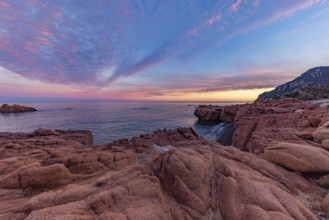 Large red rocks at the edge of the sea under a cloudy evening sky, Spiaggia di Cala E'Luas,