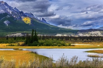 Impressive trip to the Rocky Mountains. Rocks, lakes and yellow grass under flying clouds. Concept