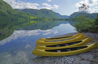 Yellow kayaks on the shore, mountain range reflected in Lake Bohinj, Triglav National Park, Julian