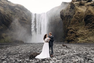 Wedding couple near Skogafoss waterfall. Destination Iceland wedding. The groom hugs the bride by