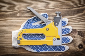 Stapler gun pair of working gloves on wooden board construction concept