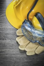 Safety gloves glasses earmuffs building helmet on wooden board