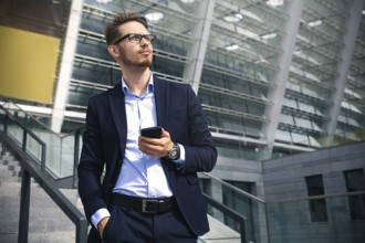 Handsome successful businessman in elegant suit outdoors walking on street in the city