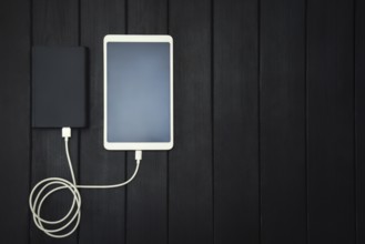 Power bank loads tablet PC, smartphone, isolated on wooden background. charging concept. free
