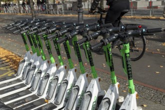 Traffic, mobility, cyclists and lined-up e-scooters from Lime in autumn on a street in Berlin,