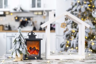 Key and tiny house of a small size on cozy home with Christmas decor on table of festive white